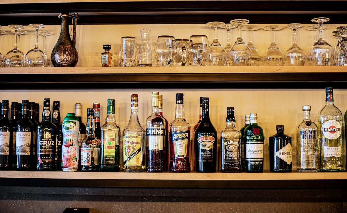 The bar with bottles and glasses on wooden shelves