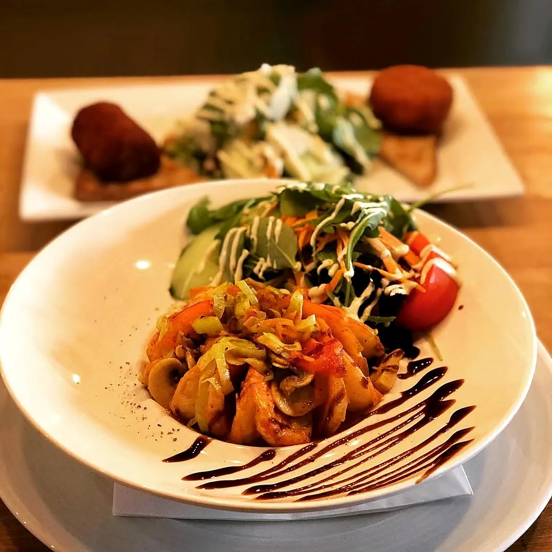 A plate of scampi and salad, with croquettes behind it