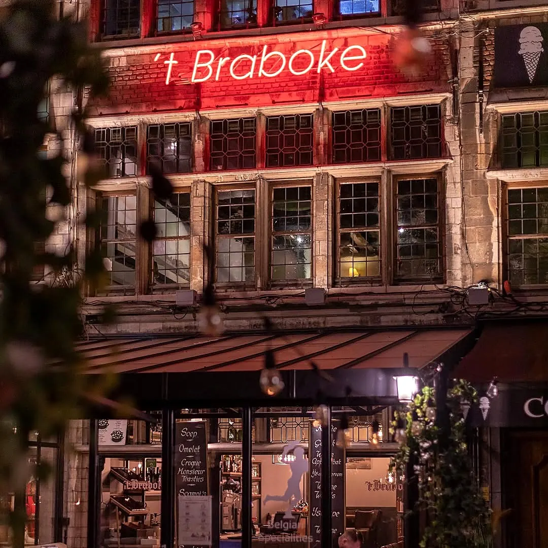 The front of 't Braboke on the Grote Markt at night, with its name in red light