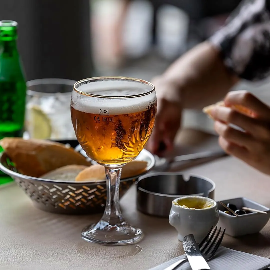 A Belgian beer on the table, with bread and olives