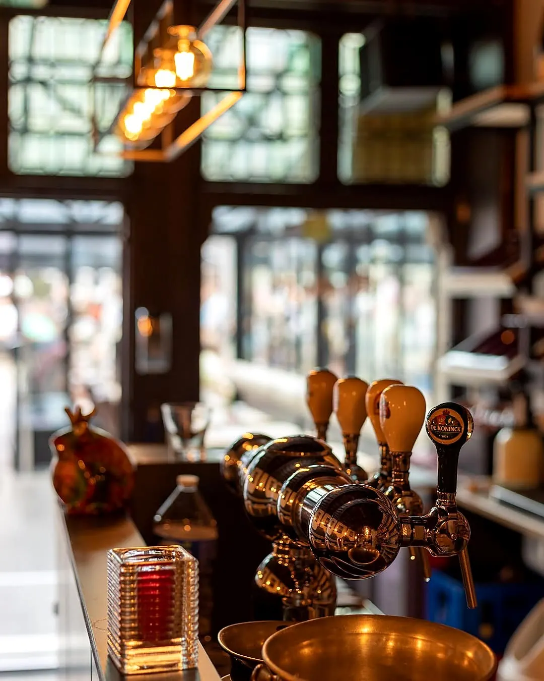 Copper beer tap at the bar of 't Braboke, with the square in the background